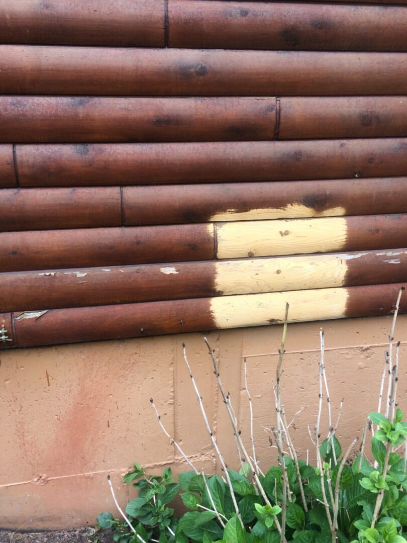A brown log wall with yellow paint on it.