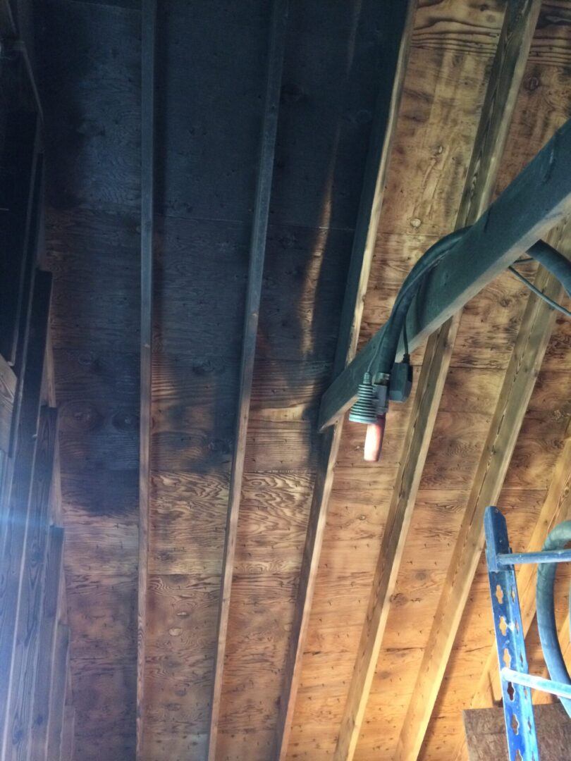 A ceiling with some wooden beams and wires